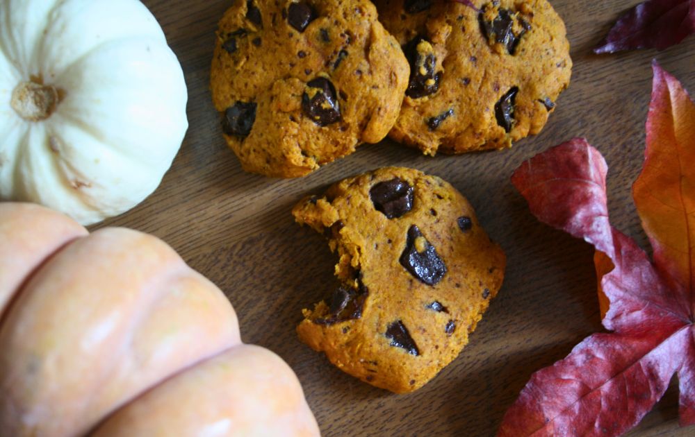drei Pumpkin Spice Chocolate Chip Cookies inzwischen Kürbissen und Blättern